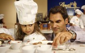 De avental, Federer põe criançada para fazer chocolate em fábrica na Suíça